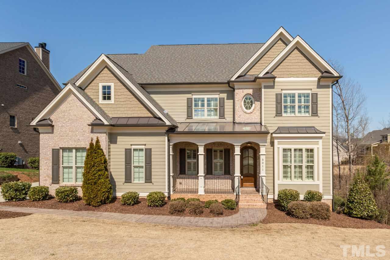 5011 Pomfret Point Raleigh, NC 27612 - Photo 1 of 25 Exterior features include fiber cement siding with brick and shake accents, inviting covered front porch, and extensive landscaping.