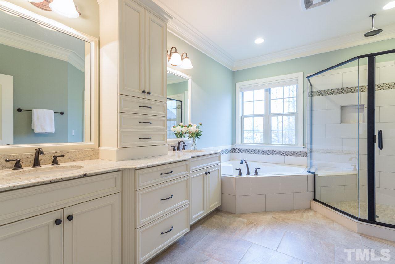 5011 Pomfret Point Raleigh, NC 27612 - Photo 13 of 25 The well-appointed master bath offers dual vanities with a floor-to-ceiling storage cabinet between them, framed bath mirrors, a private water closet ( toilet room), a jetted tub and large walk in shower with rain shower head and tile surround.