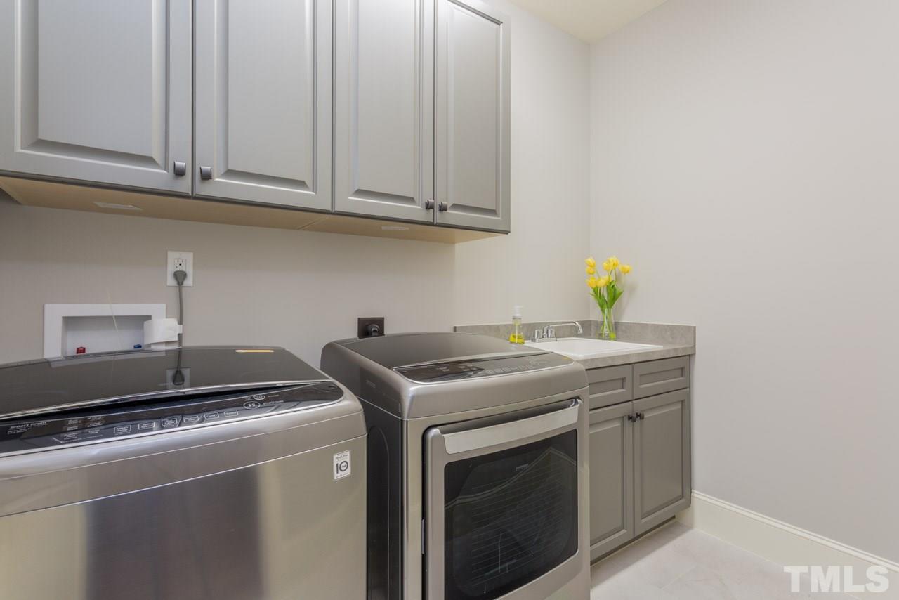 5011 Pomfret Point Raleigh, NC 27612 - Photo 19 of 25 The laundry room features built-in cabinets, a utility sink, tile floors, washing machine and dryer.