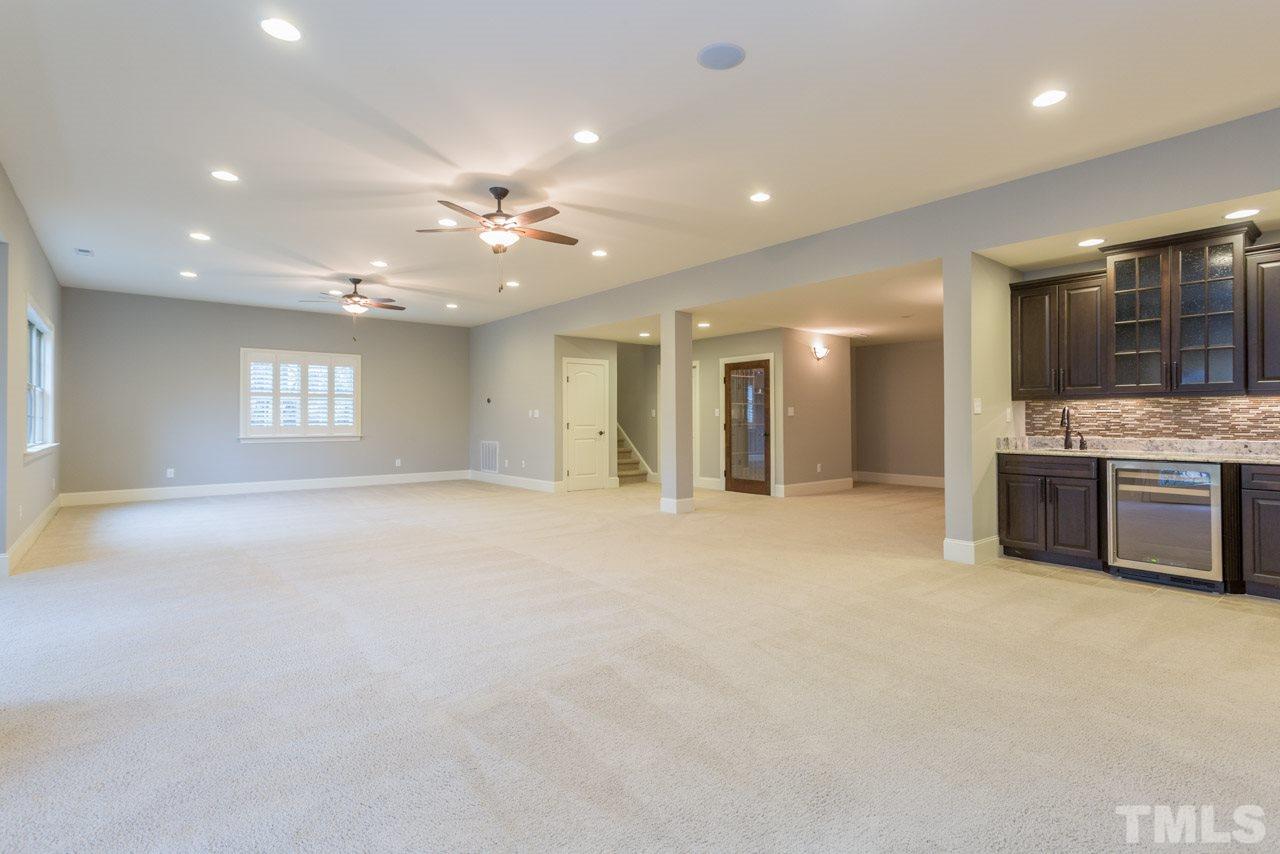 5011 Pomfret Point Raleigh, NC 27612 - Photo 21 of 25 The basement features a built in bar with a beverage/wine fridge, granite counter tops, tile backsplash and under cabinet lighting. It is located beside the media room area. The basement is pre-wired for speakers.