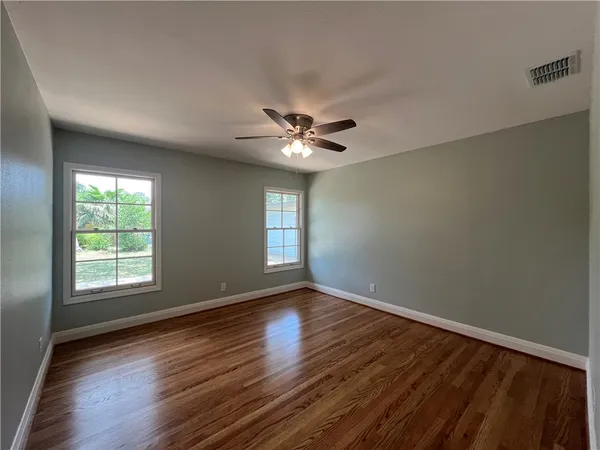 an empty room with wooden floor and windows