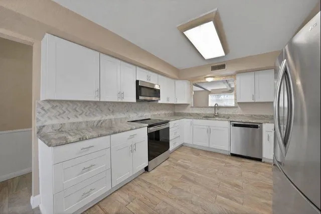 a kitchen with granite countertop white cabinets and stainless steel appliances