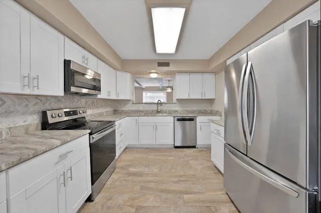a kitchen with a refrigerator a sink and a stove top oven