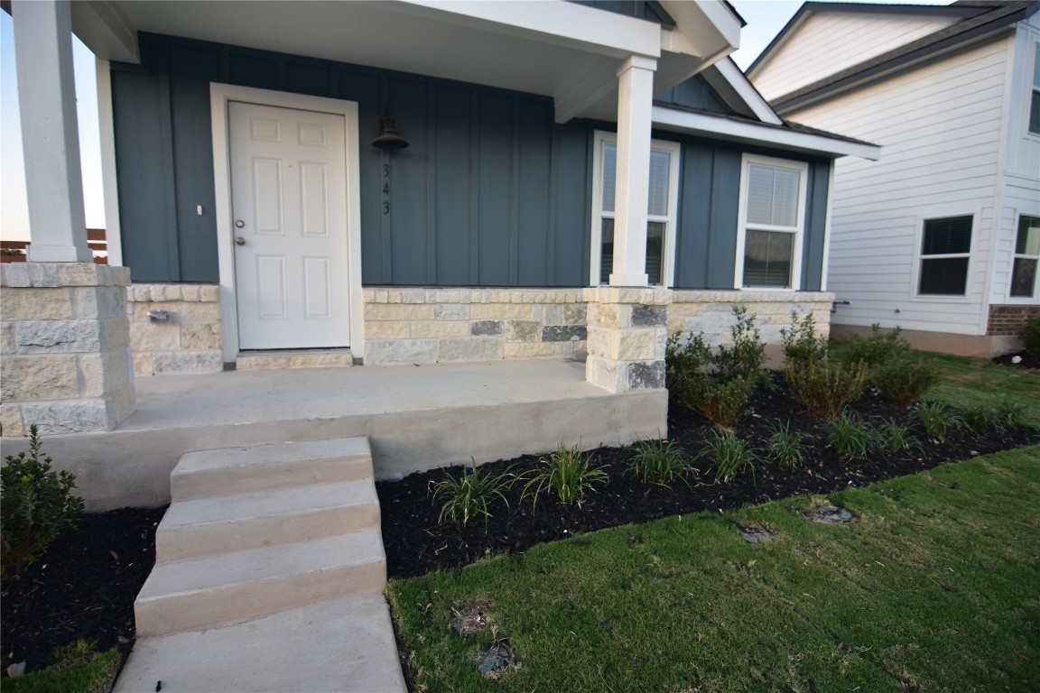 343 Keefer Kyle, TX 78640 - Photo 34 of 38 Doorway to property featuring board and batten siding, covered porch, stone siding, and a lawn