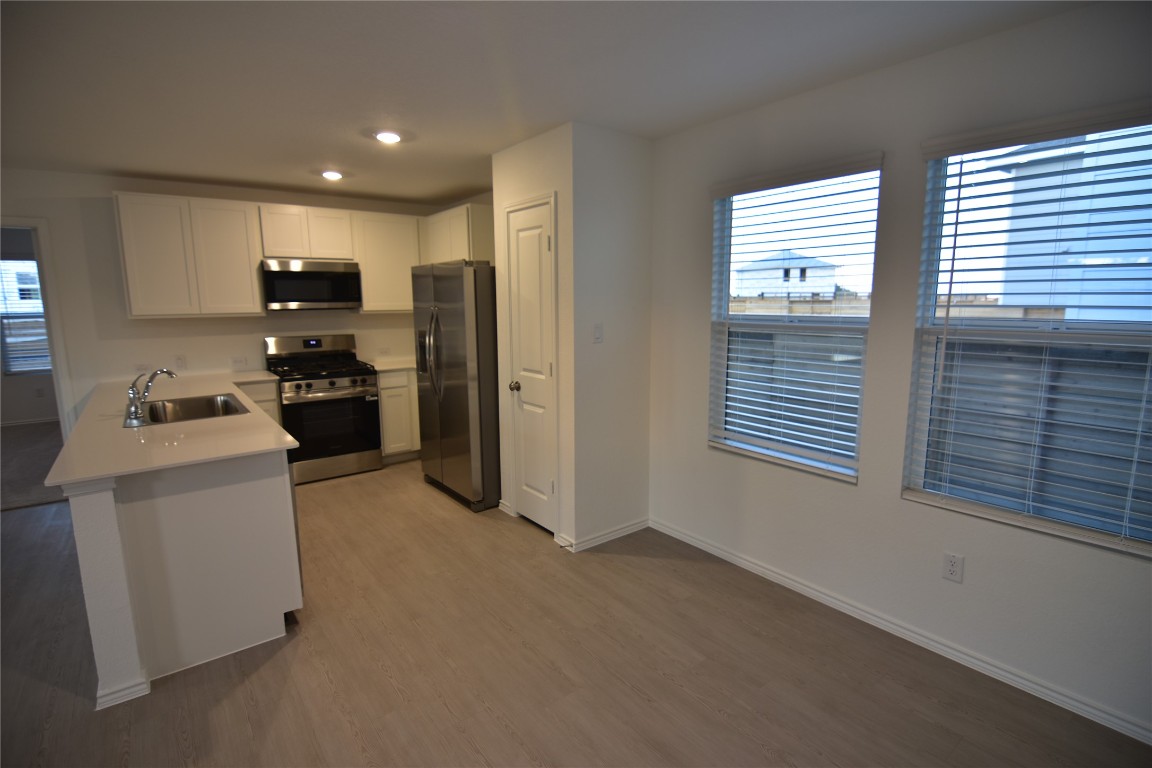 343 Keefer Kyle, TX 78640 - Photo 4 of 38 Kitchen featuring white cabinets, light countertops, stainless steel appliances, light wood-style flooring, and a peninsula
