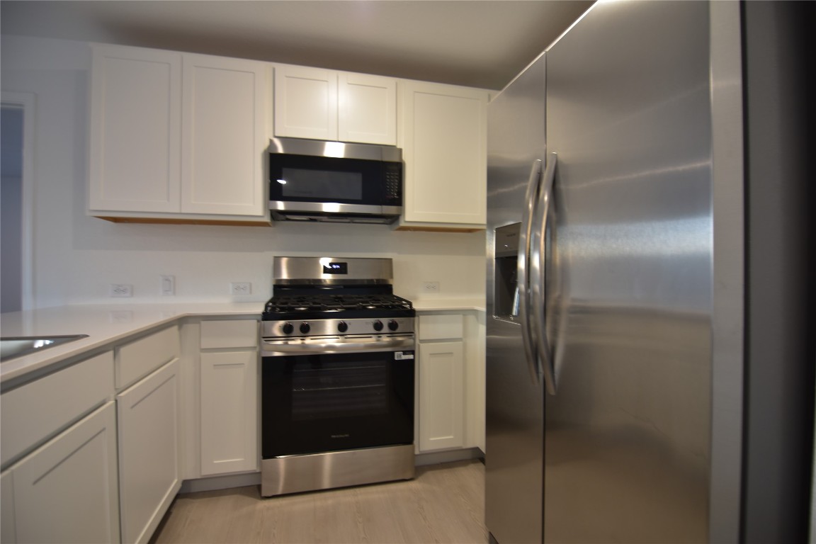 343 Keefer Kyle, TX 78640 - Photo 8 of 38 Kitchen with appliances with stainless steel finishes, white cabinetry, and light wood finished floors