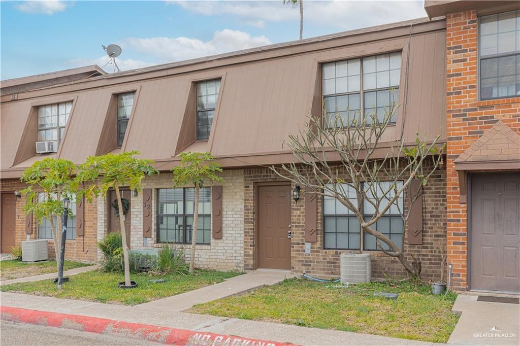 2201 South Jackson Road, Unit 31M Pharr, TX 78577 - Photo 13 of 13 Brick exterior featuring multiple window units, decorative shutters, and a brown mansard-style roof