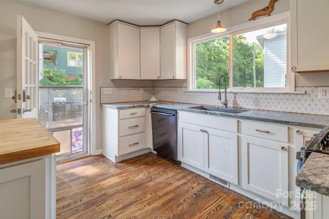 a kitchen with granite countertop a sink cabinets stainless steel appliances and a large window