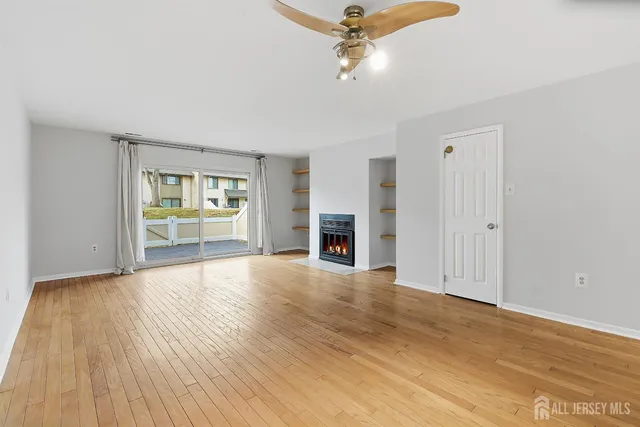 an empty room with wooden floor fireplace and windows
