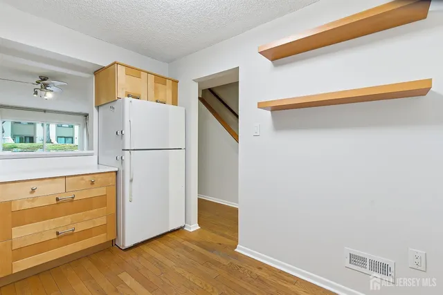 a view of a kitchen with wooden floor and a refrigerator