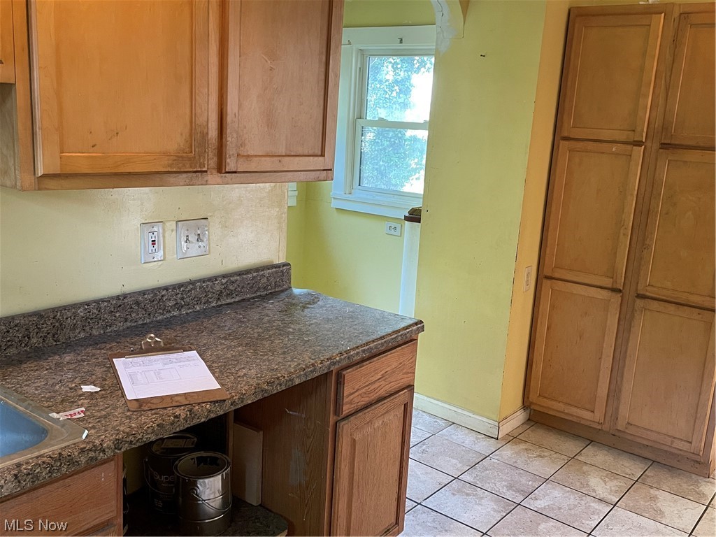1730 Wood Road Cleveland Heights, OH 44121 - Photo 15 of 34 Kitchen featuring dark countertops, light tile floors, and brown cabinets