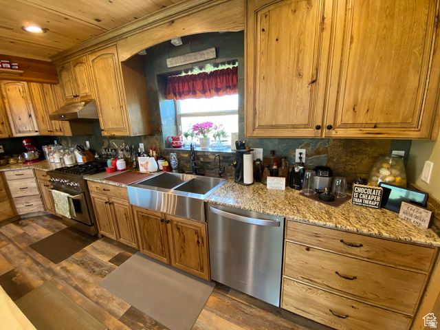 79 Auburn Forest Road Auburn, WY 83111 - Photo 17 of 76 Kitchen with stainless steel appliances, light stone countertops, wood finish cabinetry, dark wood finished floors, and wood ceiling