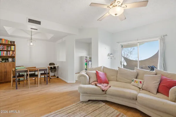 a living room with furniture kitchen view and a wooden floor