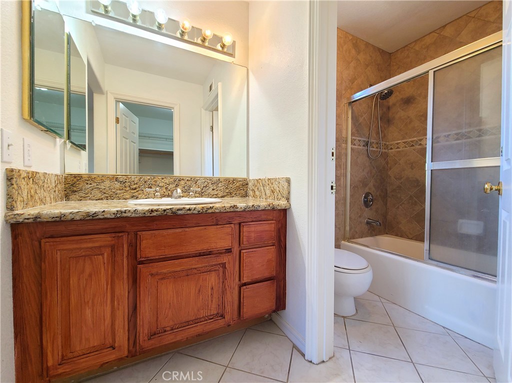 306 Edgemont Drive Redlands, CA 92373 - Photo 23 of 24 a bathroom with a granite countertop sink toilet mirror and shower