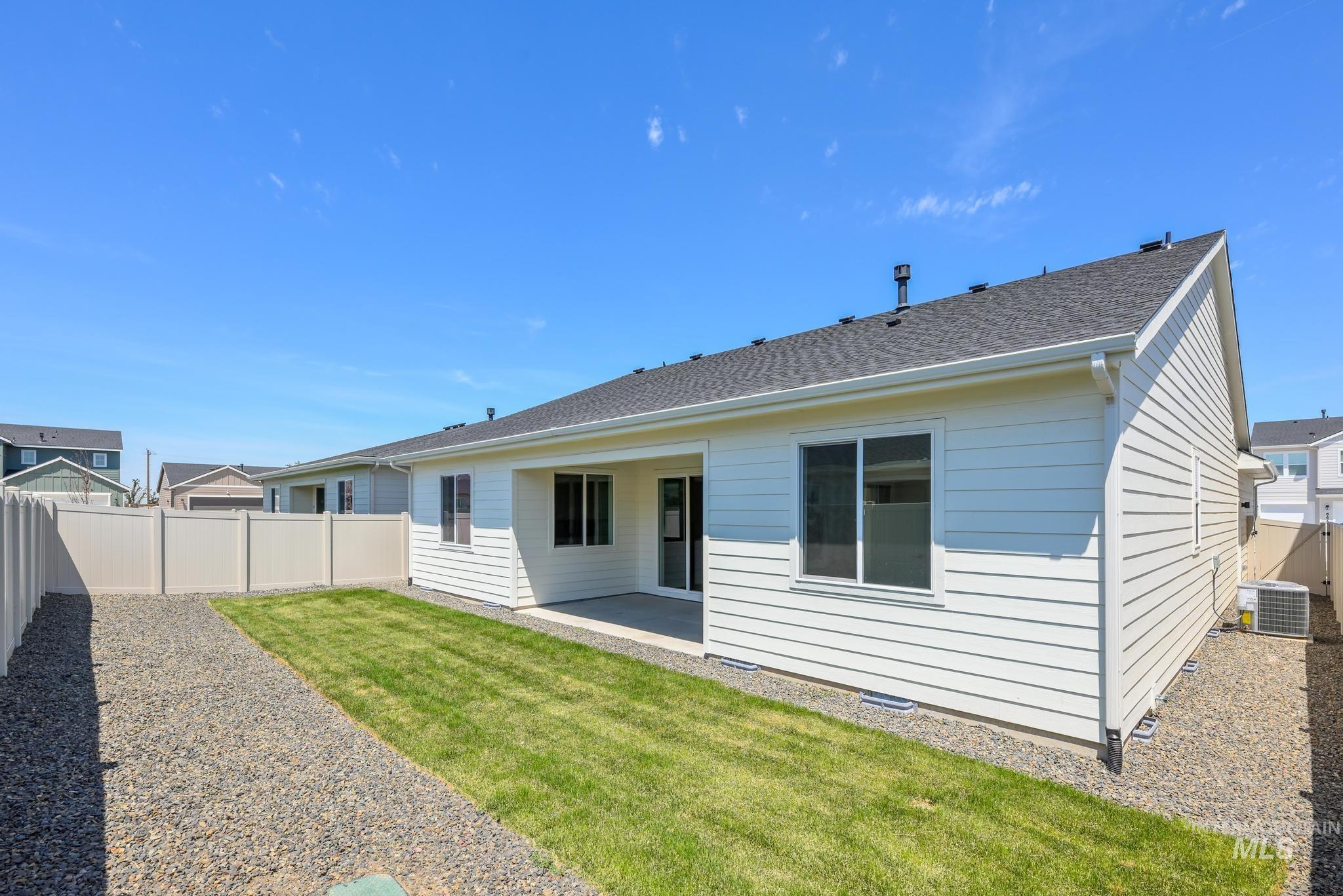 6285 West Snow Currant Street Meridian, ID 83646 - Photo 24 of 26 Rear exterior featuring white horizontal siding, a dark shingle roof, a concrete patio, and a fenced yard with a gravel path and a grass strip