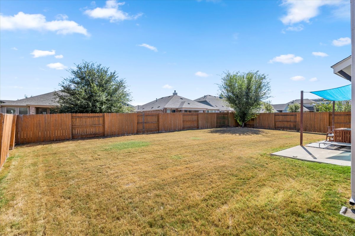 6912 Cardinal Bloom Loop Austin, TX 78744 - Photo 5 of 33 A spacious, fenced backyard offers ample room for outdoor activities and private relaxation.