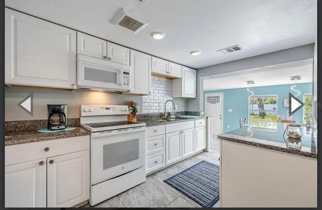 a kitchen with granite countertop white cabinets and white appliances
