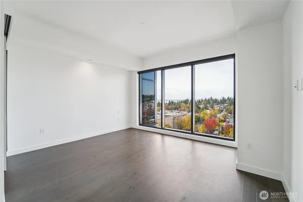an empty room with wooden floor and windows with outer view