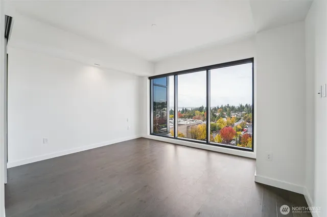 an empty room with wooden floor and windows with outer view