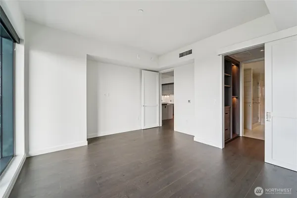 a view of an empty room with wooden floor and closet