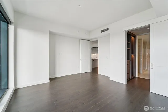 a view of an empty room with wooden floor and closet