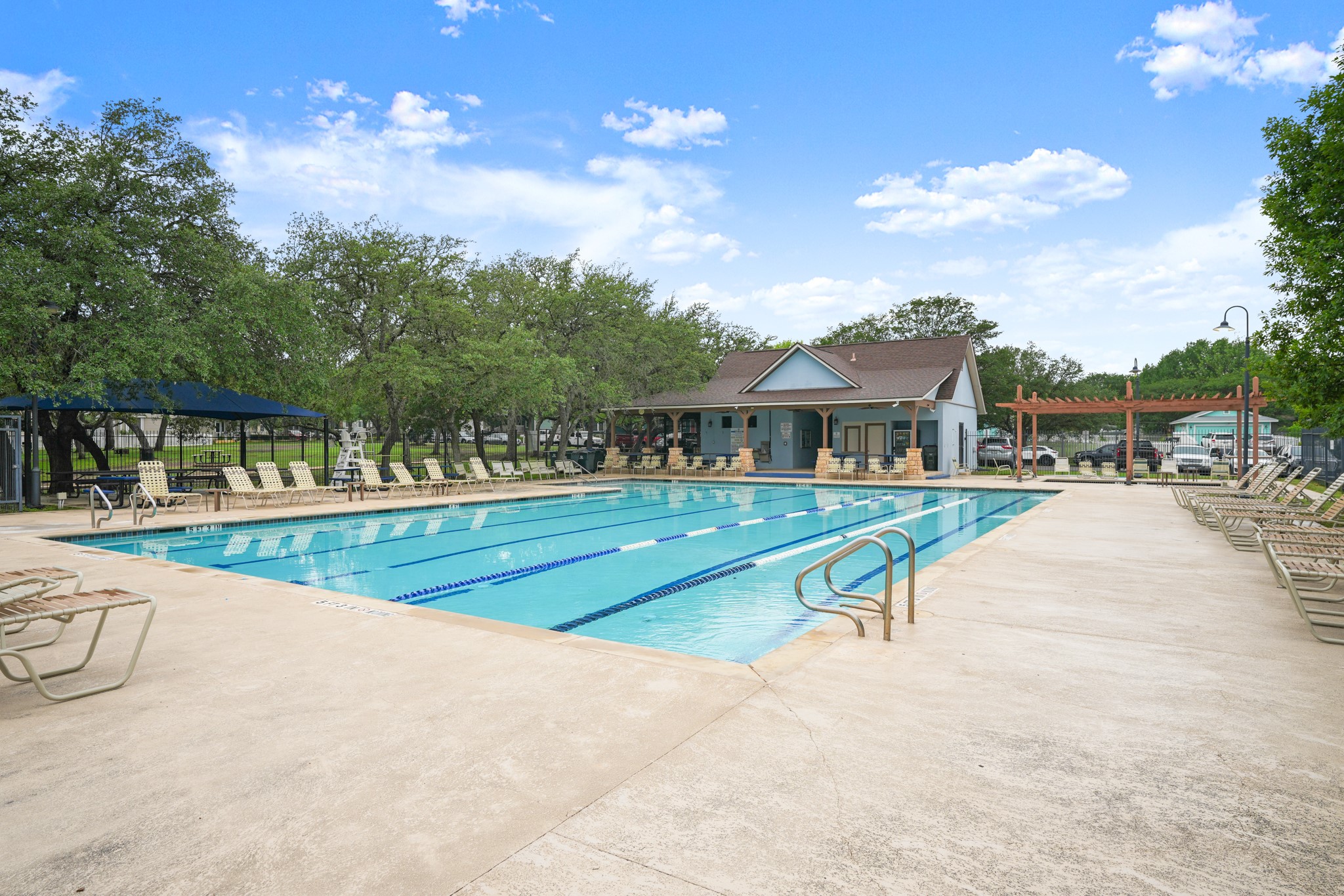 360 Sampson Kyle, TX 78640 - Photo 28 of 36 Expansive community swimming pool featuring multiple lap lanes, a surrounding concrete deck, and a clubhouse with a covered porch