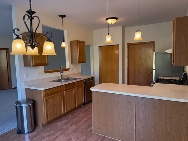 a kitchen with a chandelier a sink stainless steel appliances and cabinets