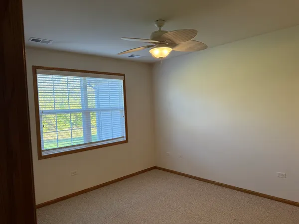 an empty room with a chandelier fan and a window