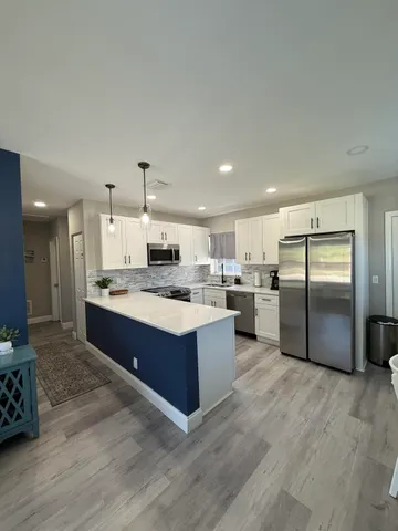 a large kitchen with a large counter top stainless steel appliances and wooden floor