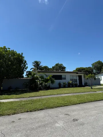 a view of a big house with a big yard and large trees
