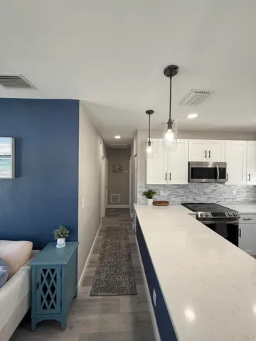 a large kitchen with kitchen island a stove a sink dishwasher and a dining table with wooden floor