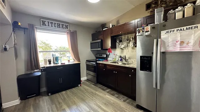 a kitchen with stainless steel appliances granite countertop a refrigerator and a wooden cabinets