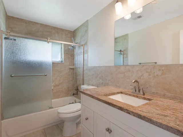 a bathroom with a granite countertop sink a toilet and shower