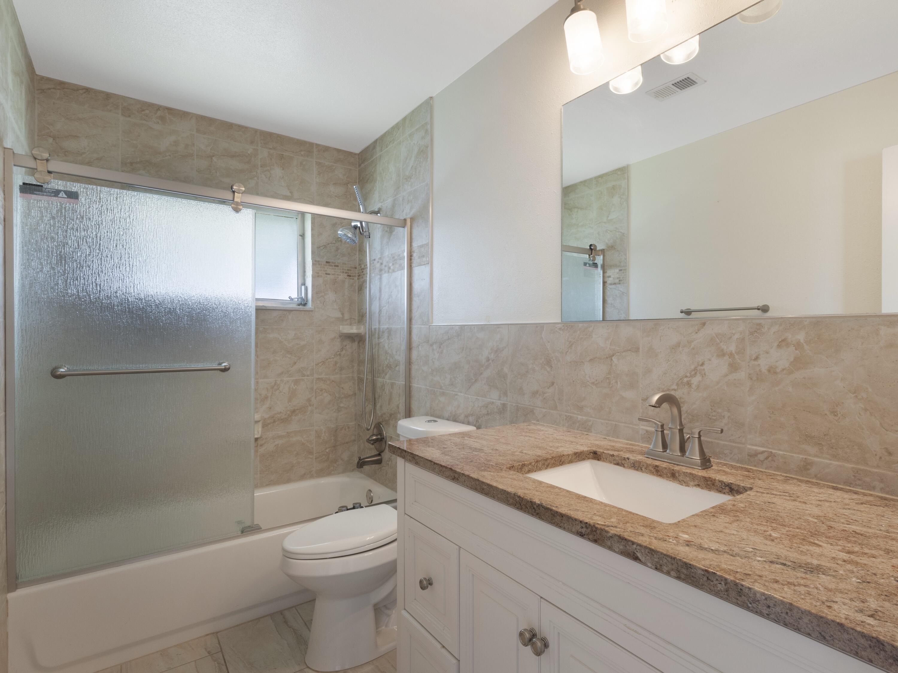 127 Leisureville Boulevard Boynton Beach, FL 33426 - Photo 11 of 23 a bathroom with a granite countertop sink a toilet and shower