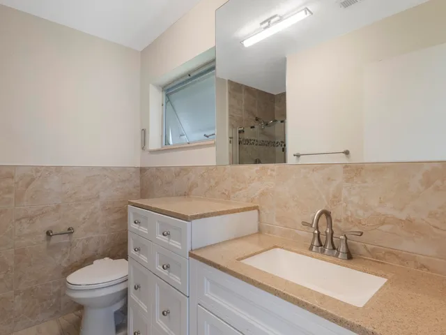 a bathroom with a granite countertop toilet sink and mirror