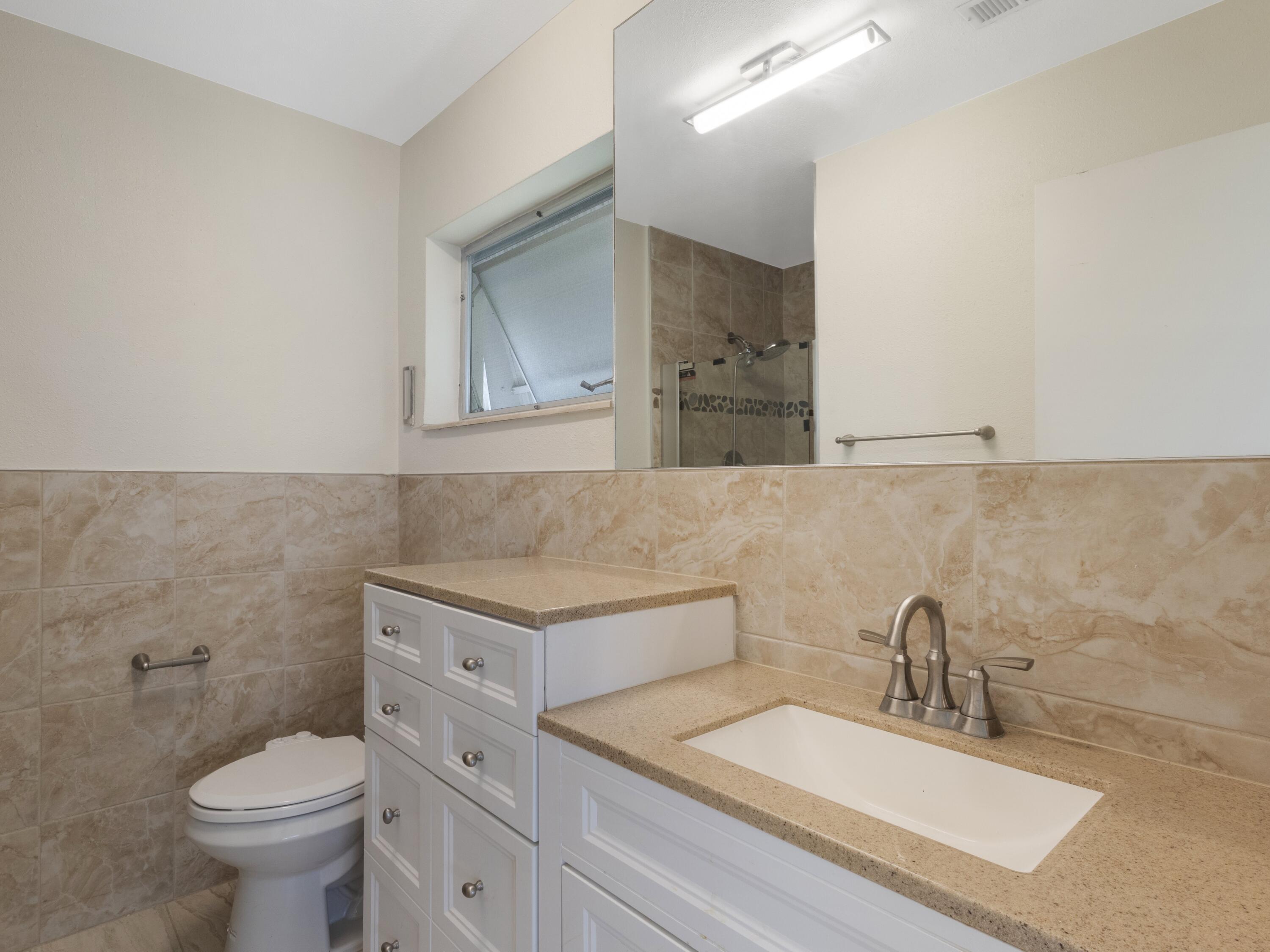 127 Leisureville Boulevard Boynton Beach, FL 33426 - Photo 15 of 23 a bathroom with a granite countertop toilet sink and mirror