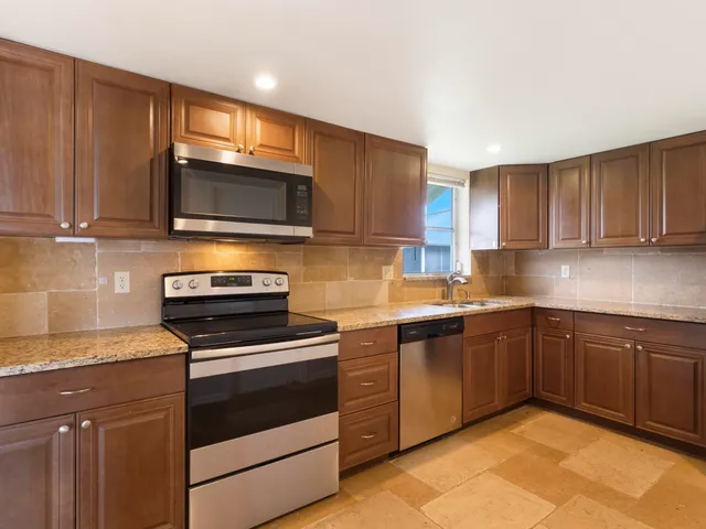 a kitchen with stainless steel appliances granite countertop wooden cabinets stove top oven and sink