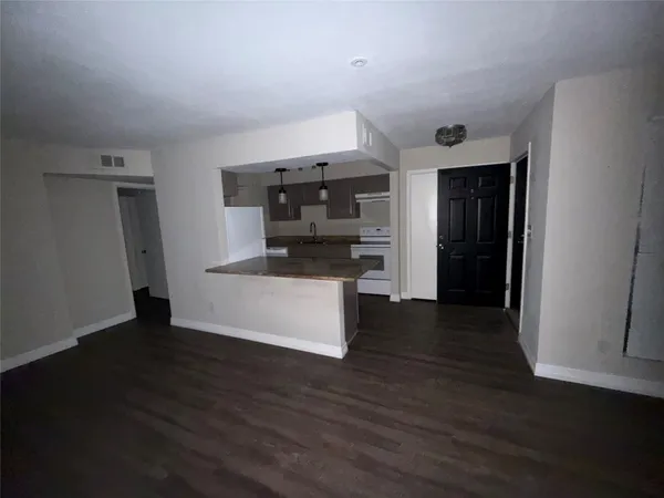 a view of an empty room with wooden floor and a ceiling fan