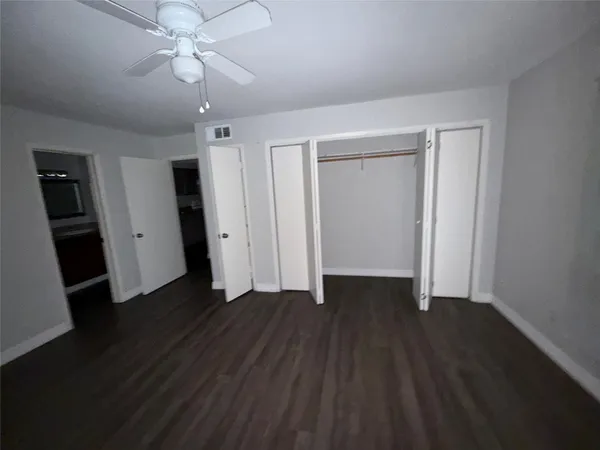 an empty room with wooden floor and ceiling fan