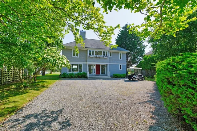 a view of a brick house next to a yard with big trees