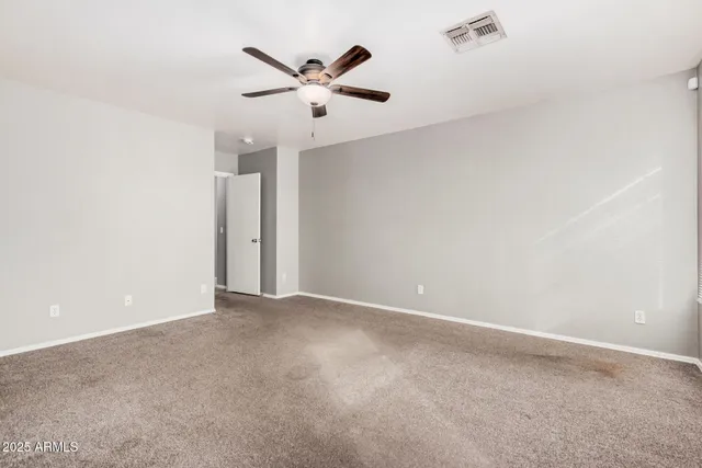an empty room with windows and ceiling fan