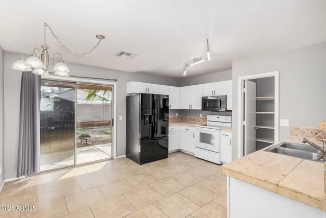 a kitchen with stainless steel appliances kitchen island granite countertop a refrigerator oven a sink dishwasher and white cabinets with a dining table and chairs