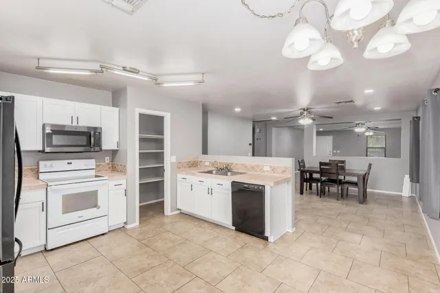 a kitchen with stainless steel appliances granite countertop a stove top oven a sink dishwasher a dining table and chairs with wooden floor