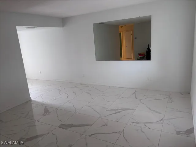 a view of a refrigerator in kitchen and an empty room in wooden floor