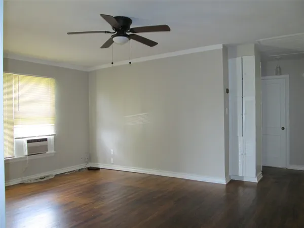a view of an empty room with wooden floor and a window