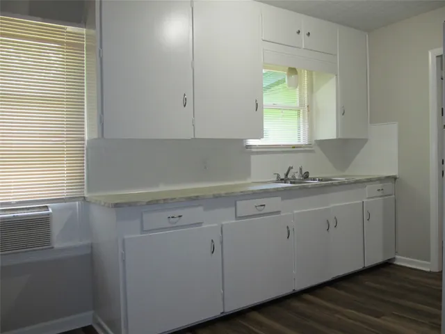 a kitchen with granite countertop white cabinets and a window