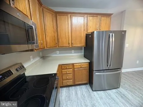 a kitchen with granite countertop a refrigerator and a stove top oven