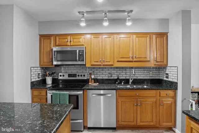 a kitchen with stainless steel appliances granite countertop a stove a sink and a microwave