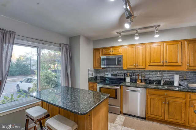 a kitchen with stainless steel appliances granite countertop a refrigerator a stove and a sink with wooden floor