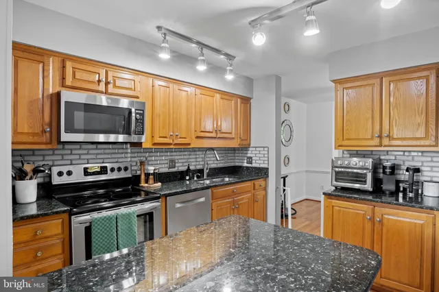 a kitchen with stainless steel appliances granite countertop a sink a stove and a refrigerator